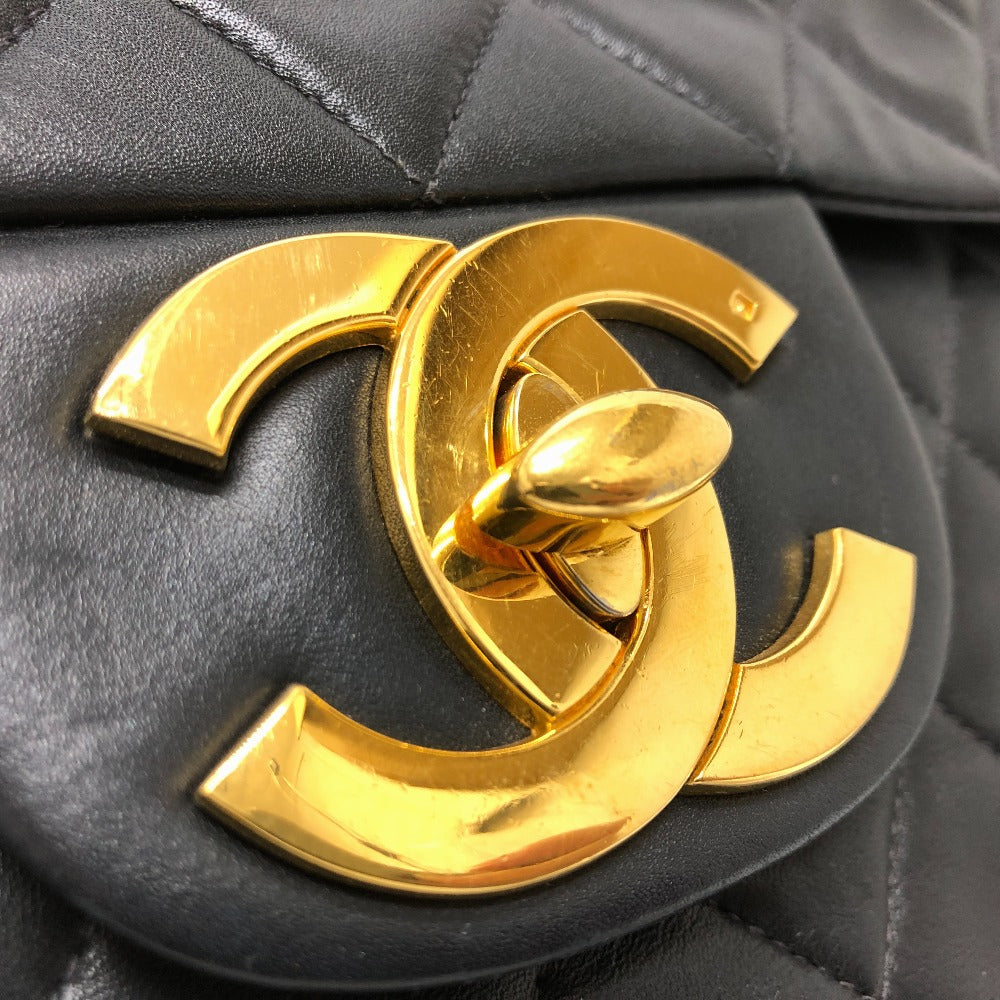 Close-up of a black quilted handbag with a gold Chanel logo.