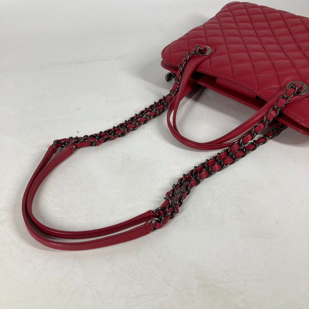 Red quilted handbag with a chain strap on a light gray background