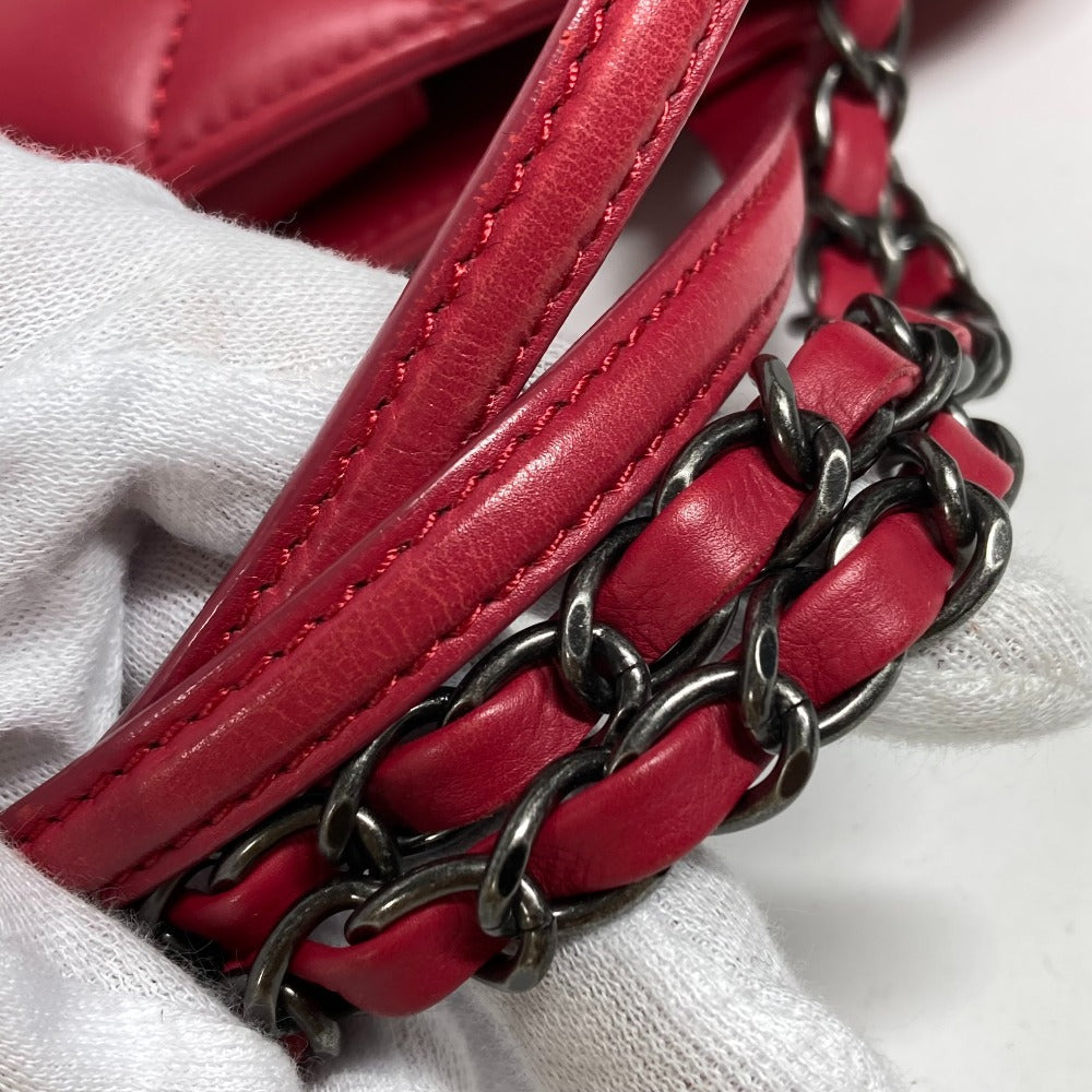 Close-up of a red leather handbag with a chain strap on a white background