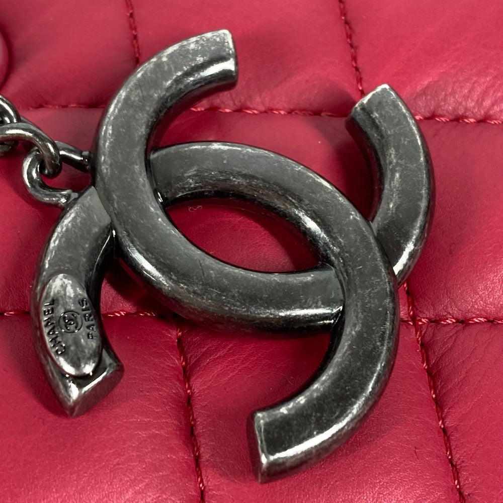 Silver Chanel logo charm on a red quilted leather surface