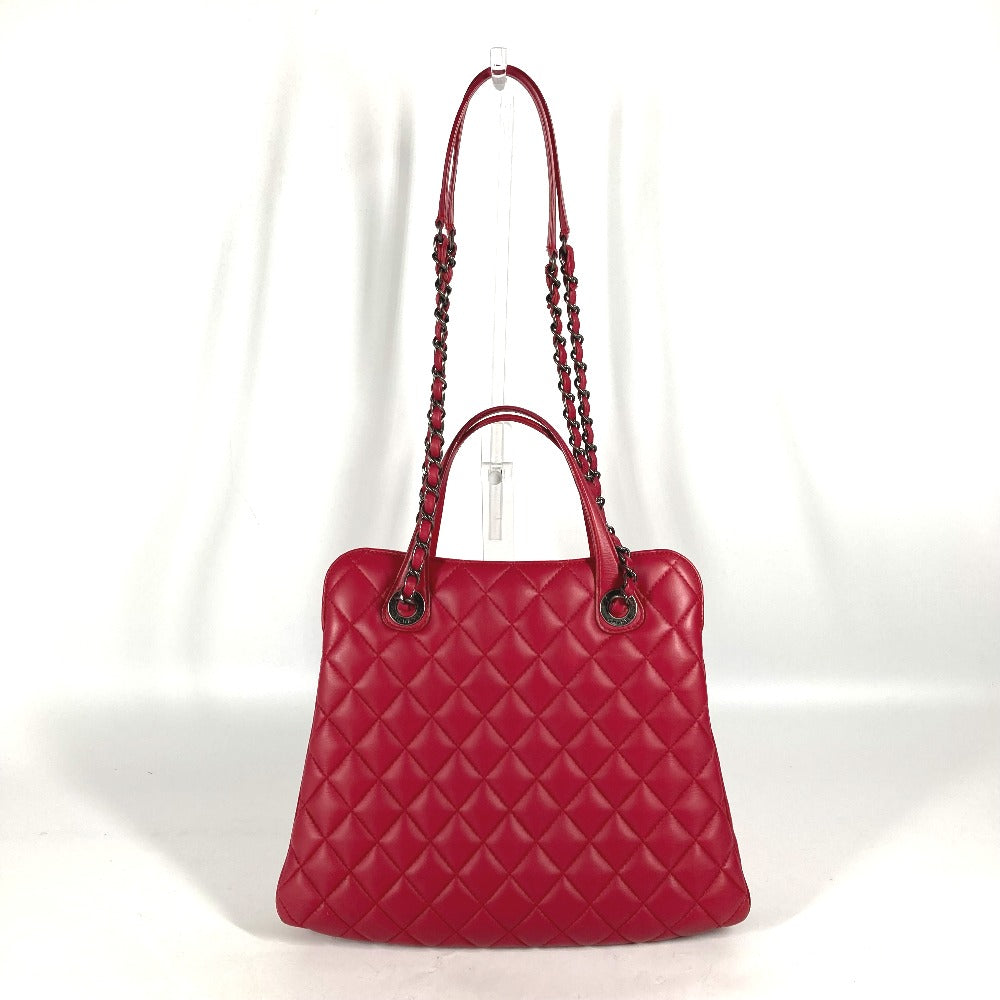 Red quilted handbag with braided handle on a white background