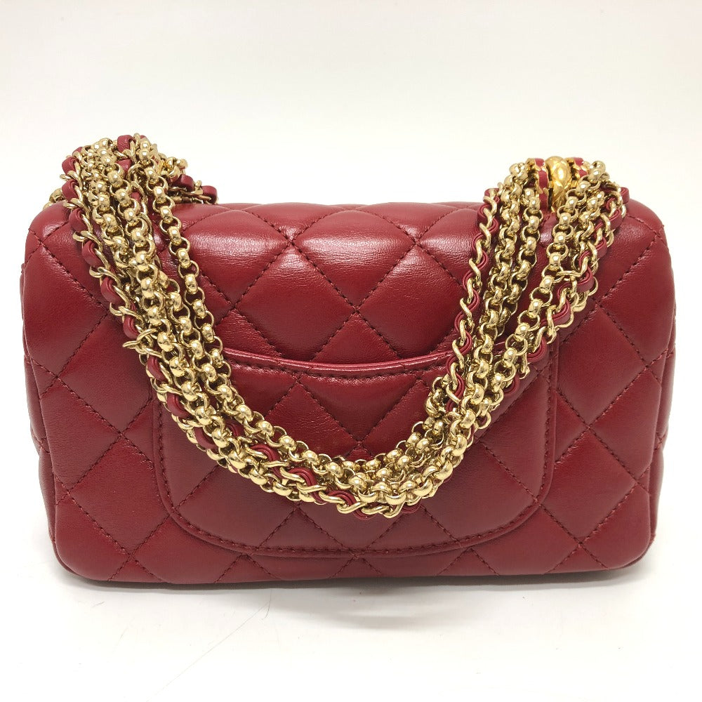 Red quilted handbag with gold chain strap on a white background