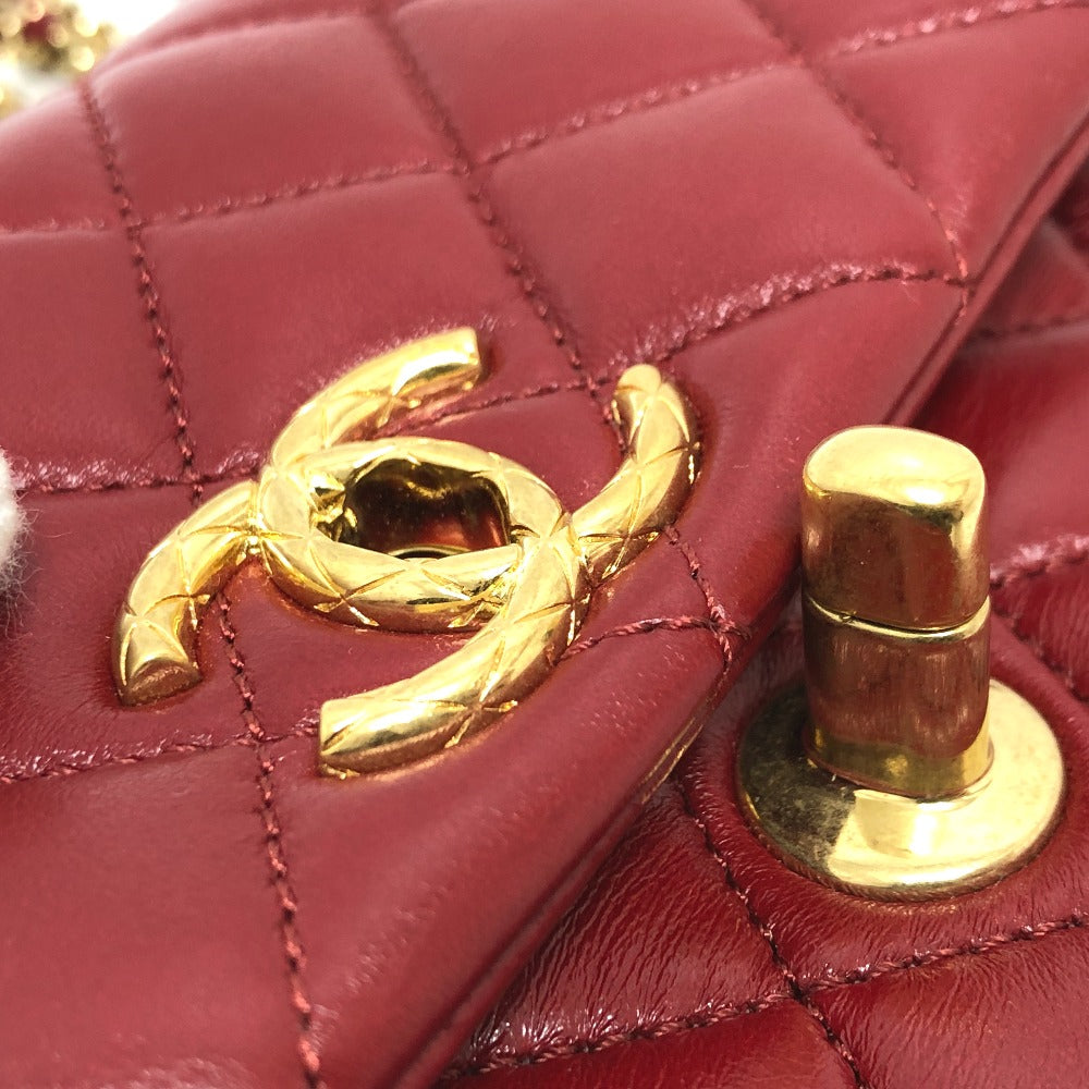 Close-up of a red quilted handbag with a gold Chanel logo and turnlock.