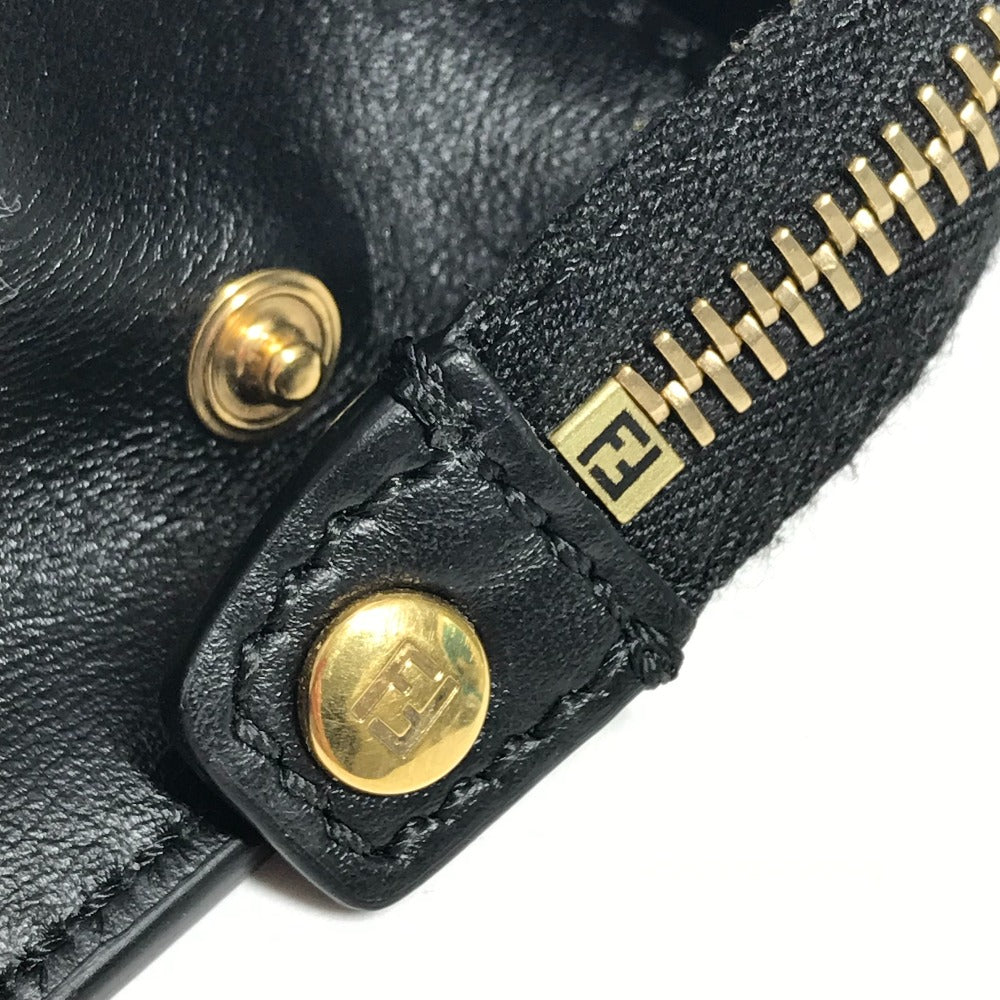 Close-up of a black leather product with gold hardware and logo.