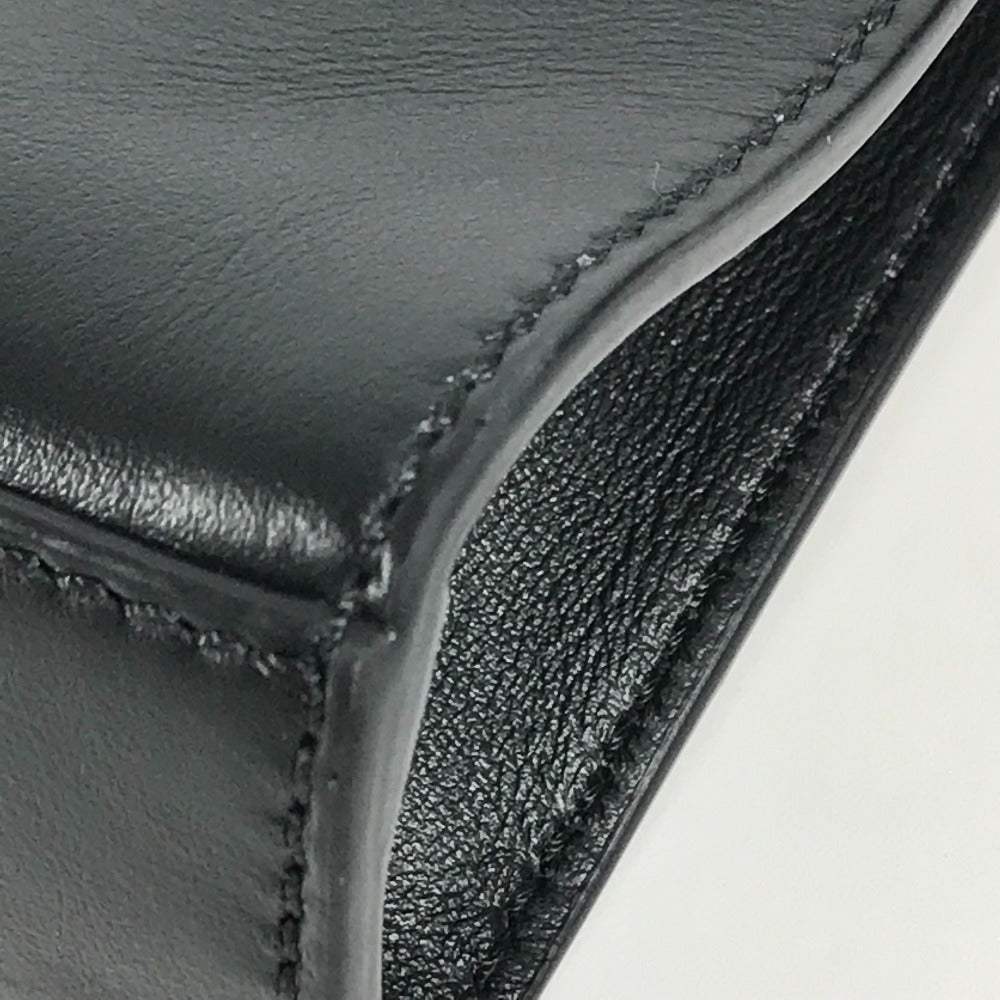 Close-up of a black leather product with visible stitching on a light gray background