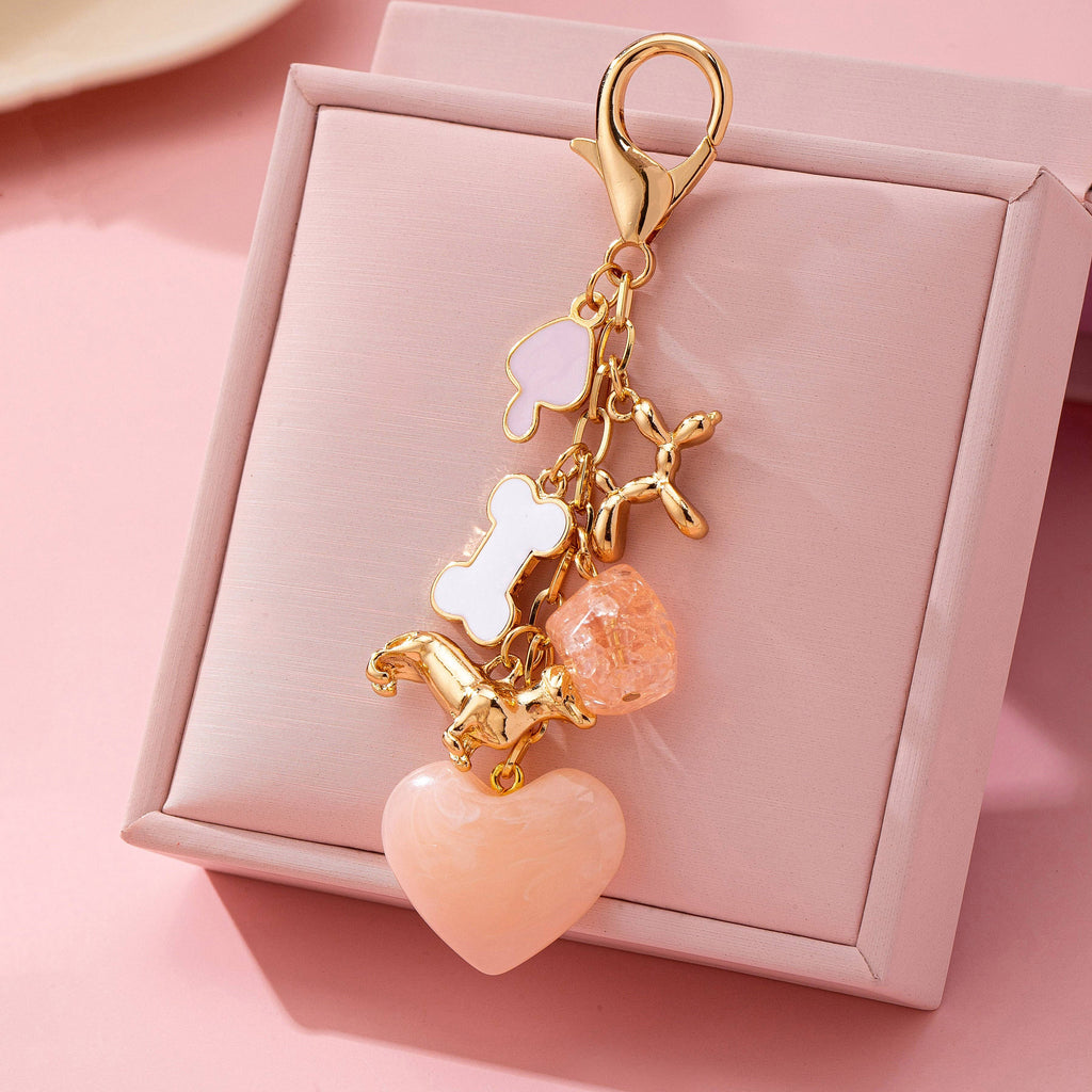 Decorative keychain with heart and bone charms on a pink box