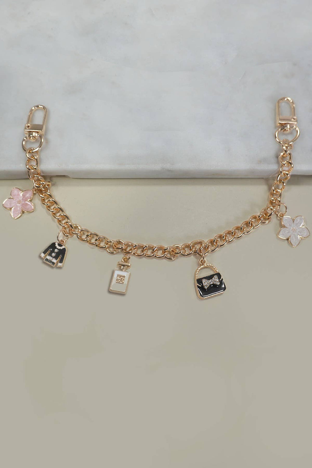 Gold bracelet with various charms on a light gray background