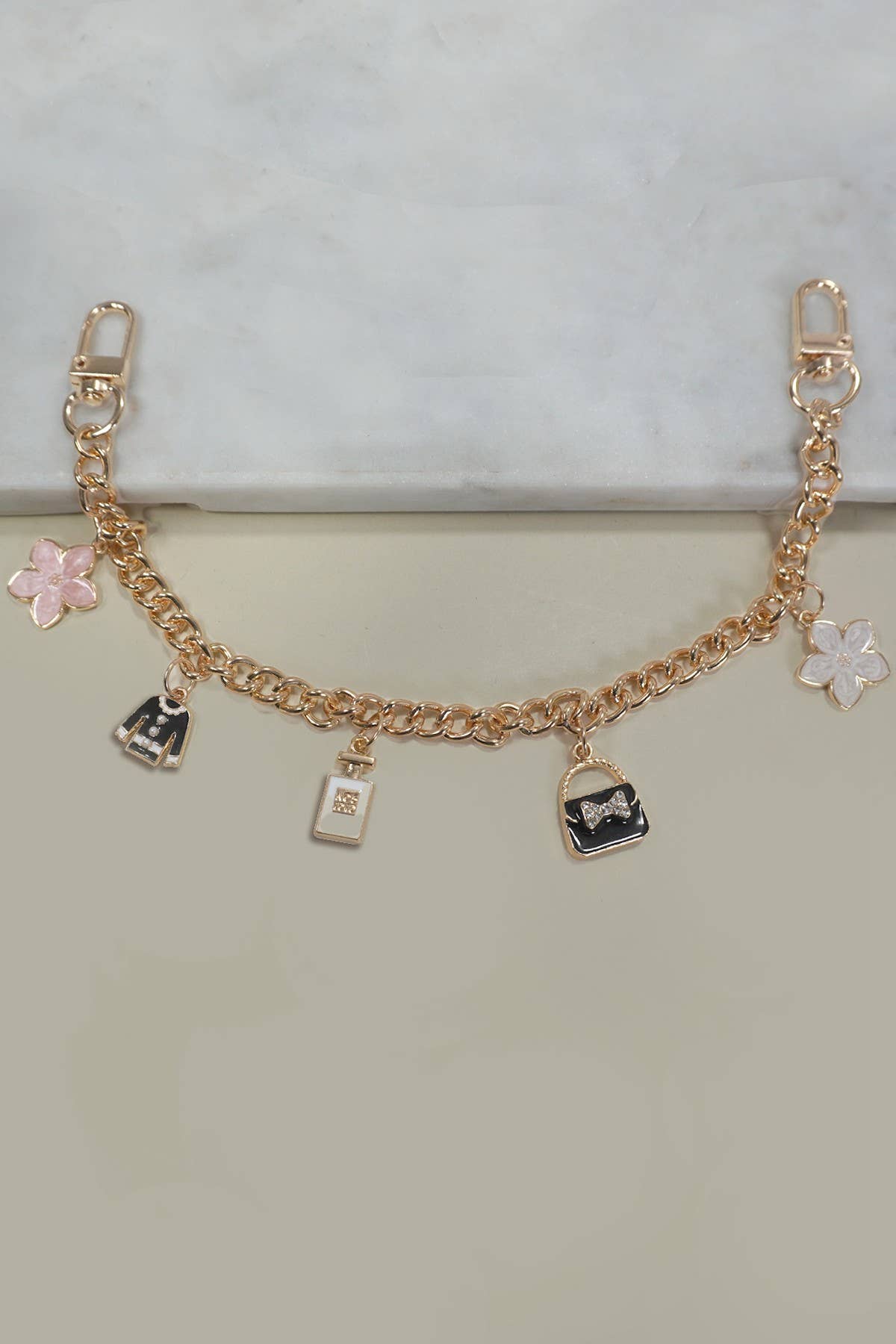 Gold bracelet with various charms on a light gray background