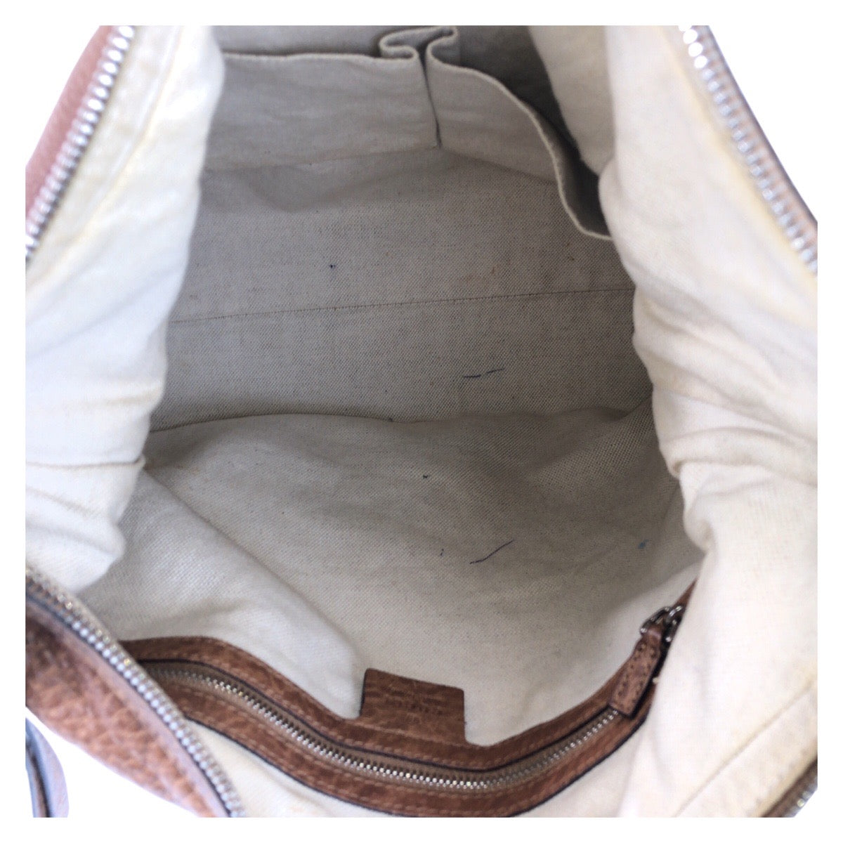 Close-up of a beige bag interior with a zipper.