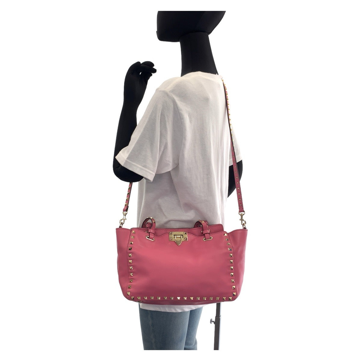 Pink handbag with studded details on a mannequin against a white background