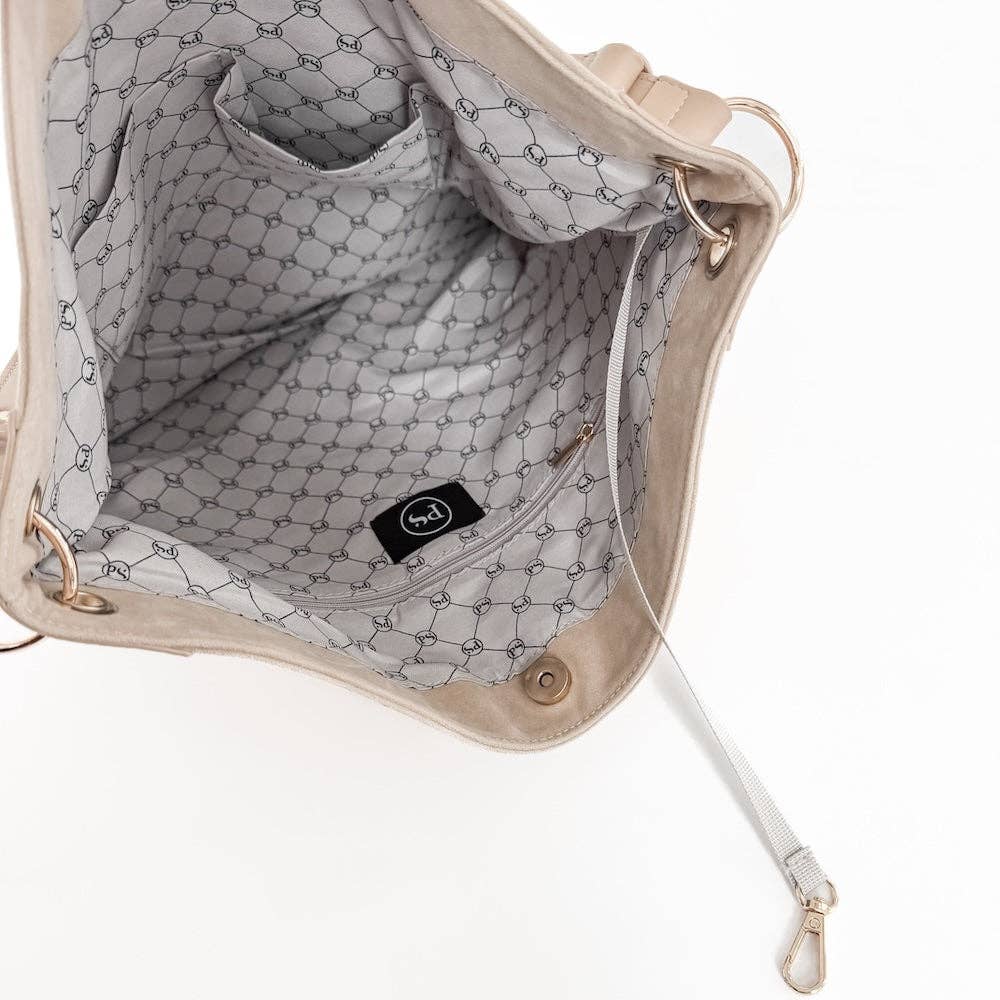 Close-up of a beige handbag with a textured interior and visible brand logo.