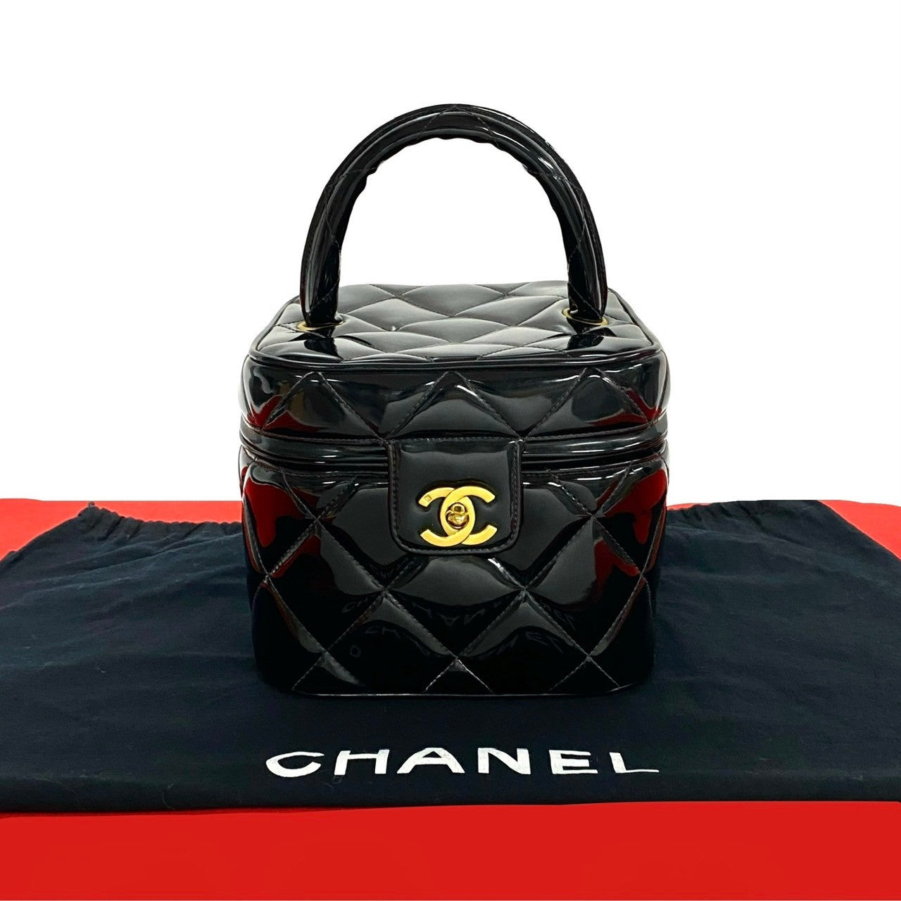 Black quilted Chanel handbag on a black and red Chanel branded surface.