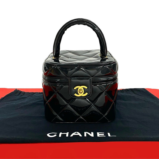 Black quilted Chanel handbag on a black and red Chanel branded surface.