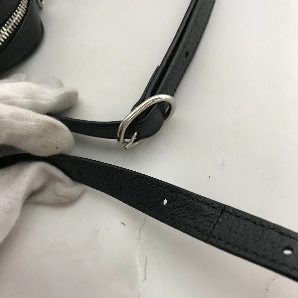 Black leather strap with silver ring held by a gloved hand on a white surface