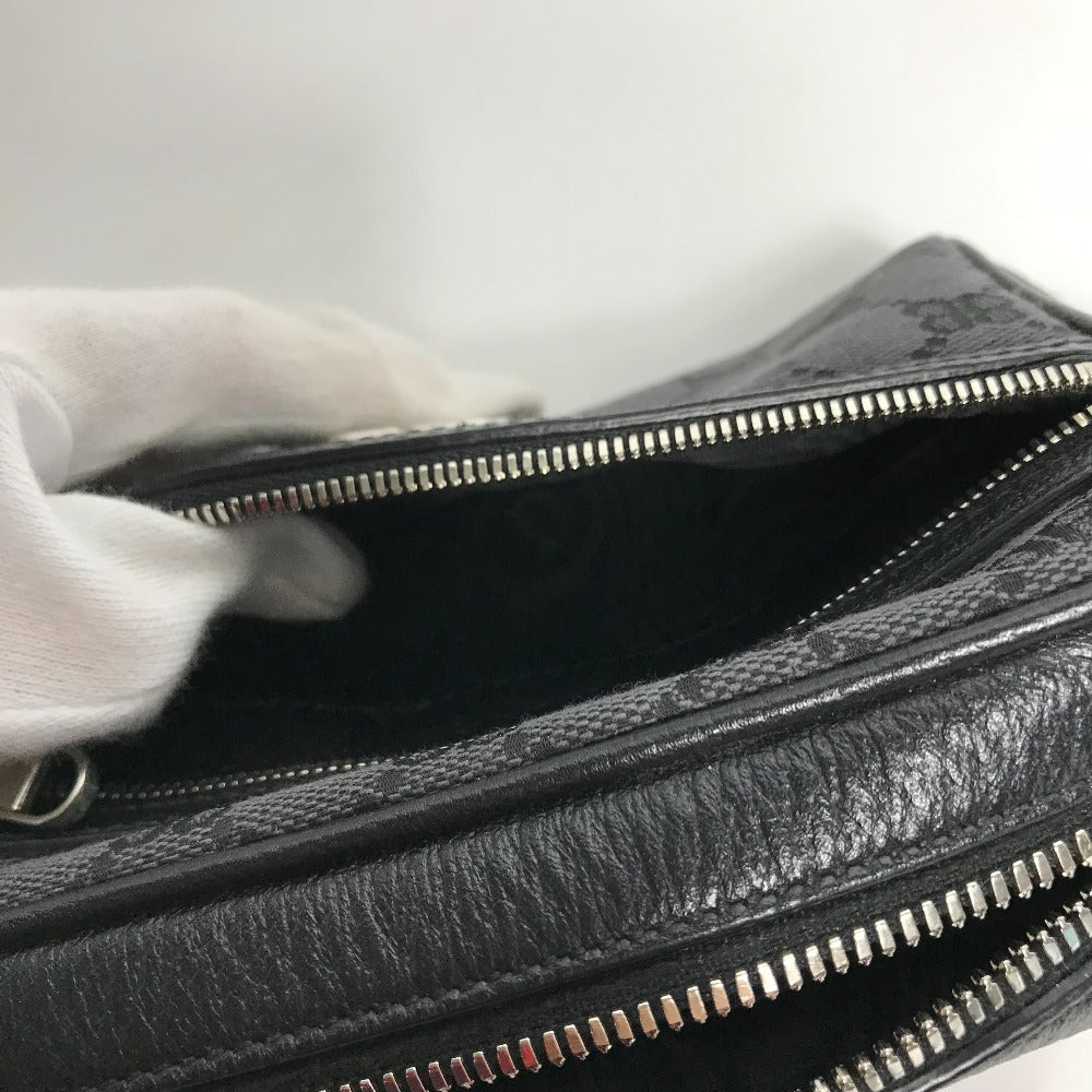 Close-up of a textured black handbag with silver zippers on a light gray background