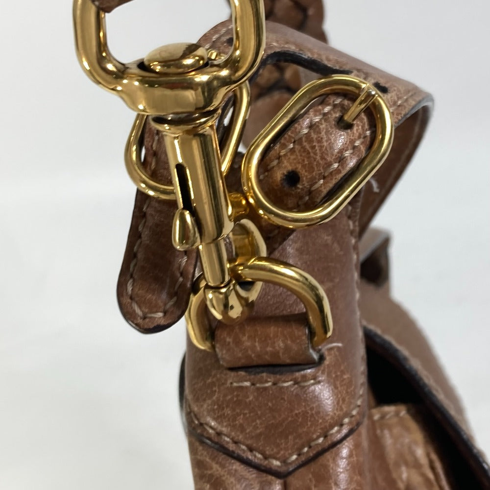 Close-up of a brown leather handbag with gold hardware on a white background