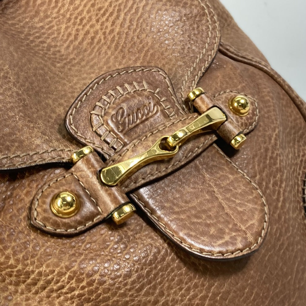 Close-up of a brown leather bag with gold hardware and a visible brand logo.