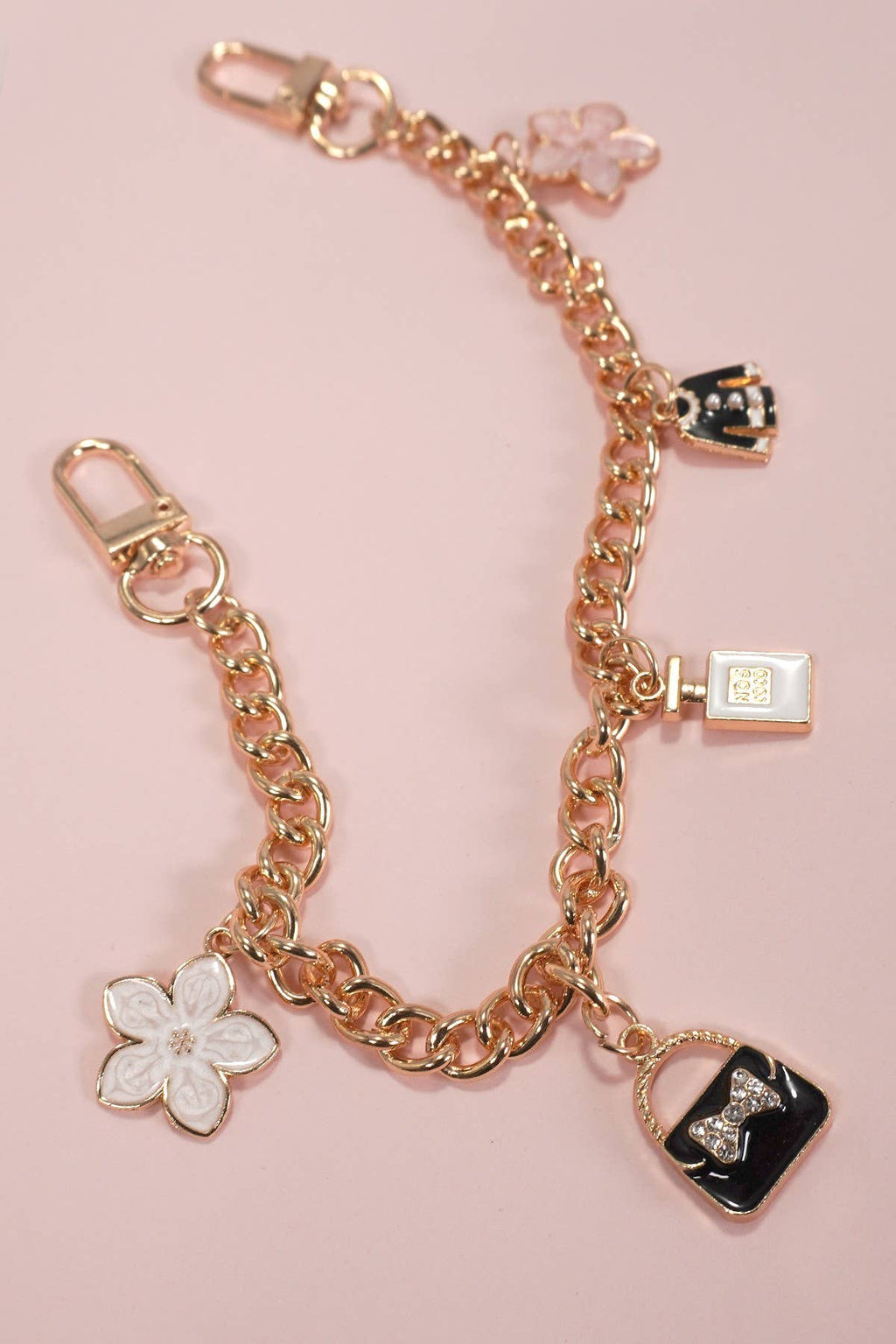 Gold chain bracelet with floral and lock charms on a pink background