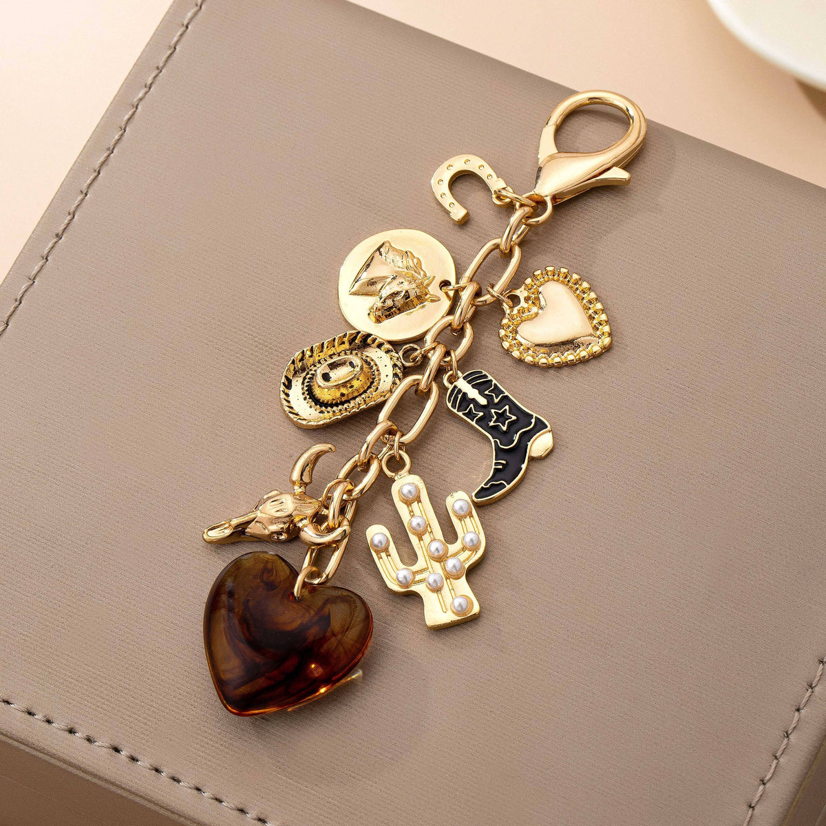 Gold keychain with various charms on a beige surface