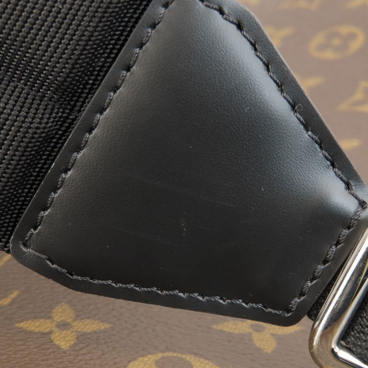 Close-up of a black leather patch on a brown textured surface with a pattern.