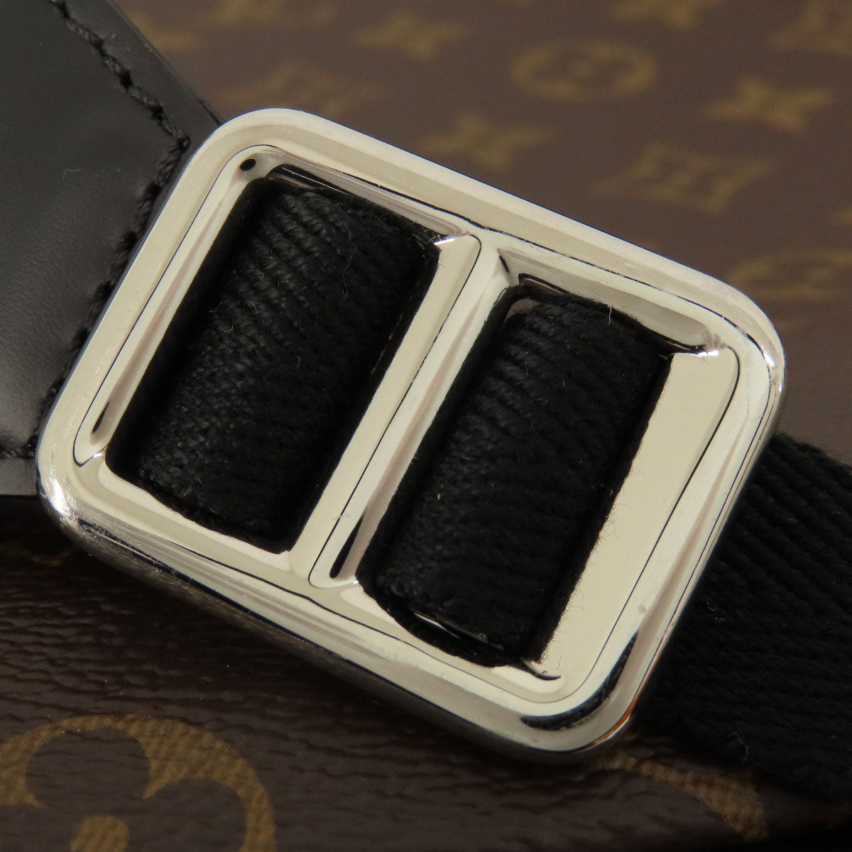 Close-up of a black leather belt with a silver buckle on a patterned background