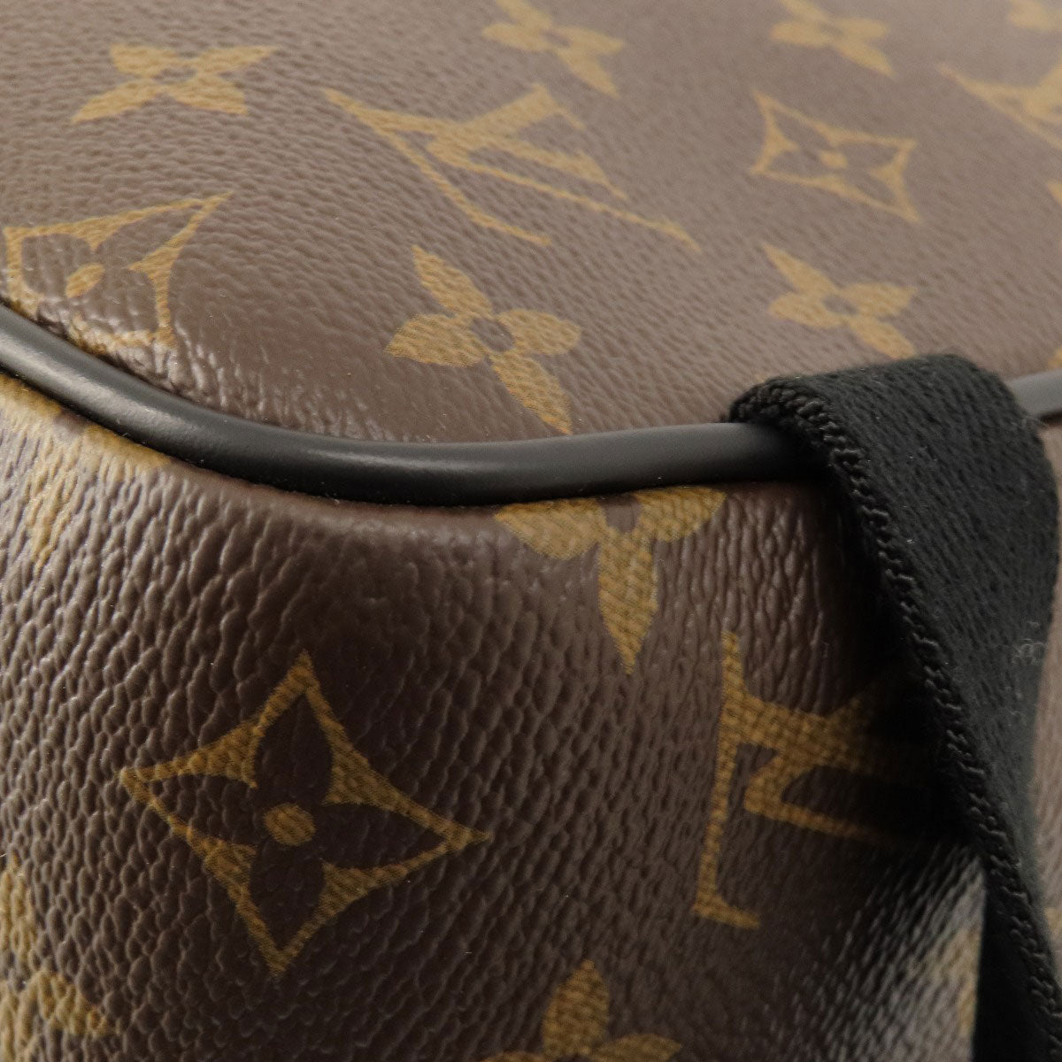 Close-up of a brown leather bag with a distinctive pattern, featuring a prominent brand logo.