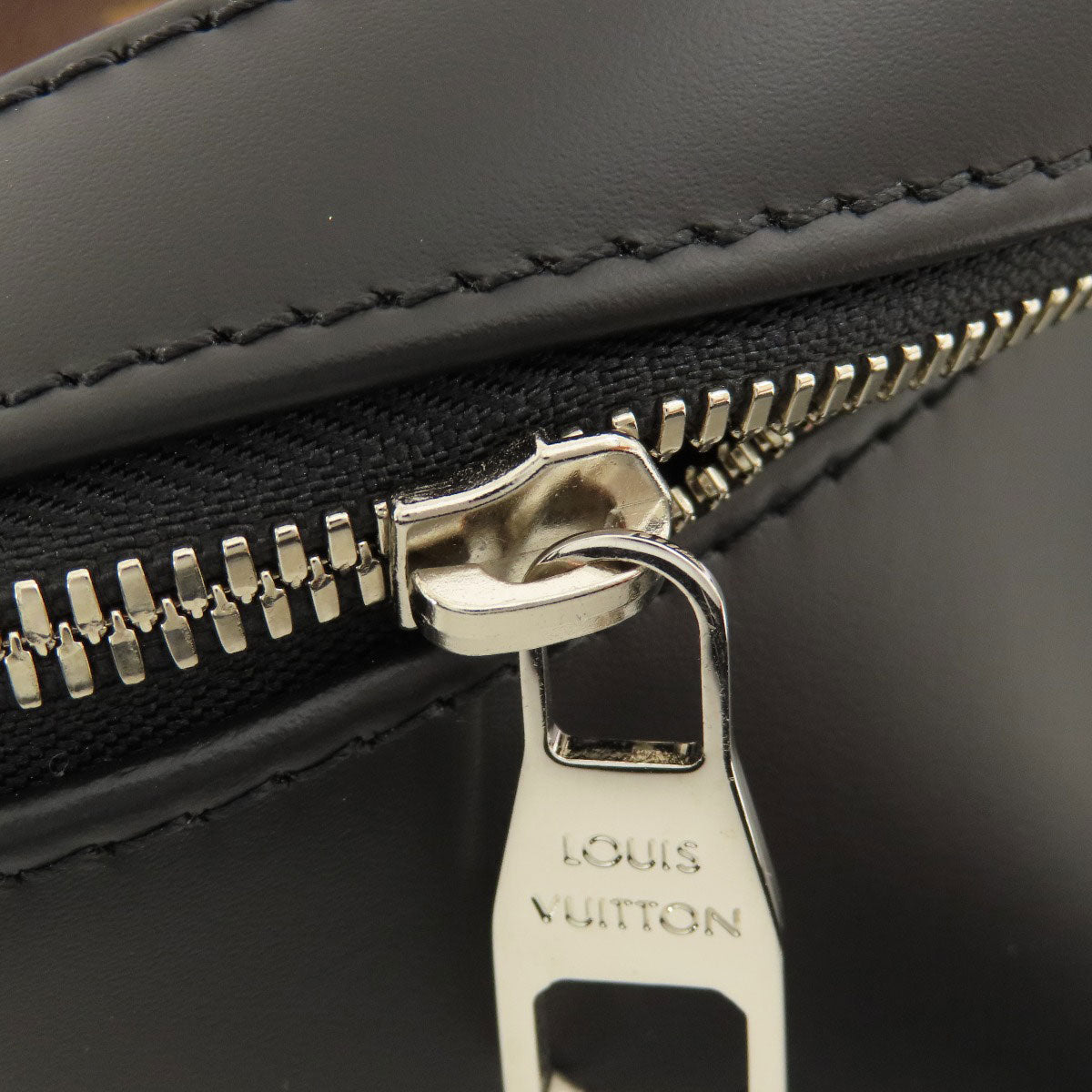 Close-up of a Louis Vuitton black leather bag with a gold zipper.