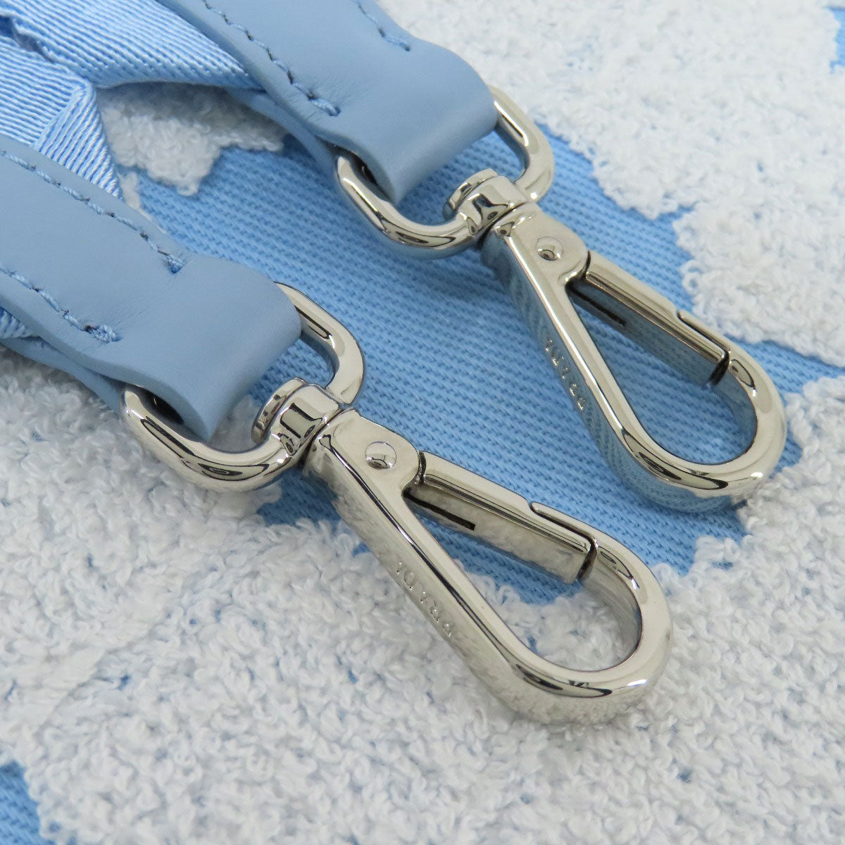 Close-up of two silver carabiners on a blue and white textured background