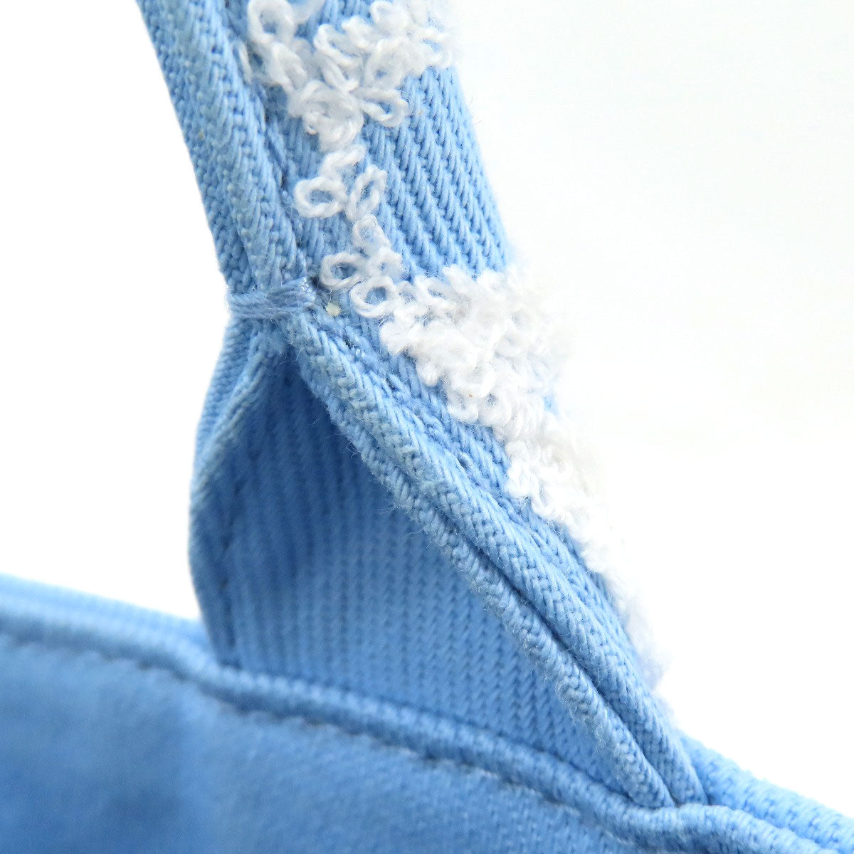 Close-up of blue fabric with white lace trim on a white background
