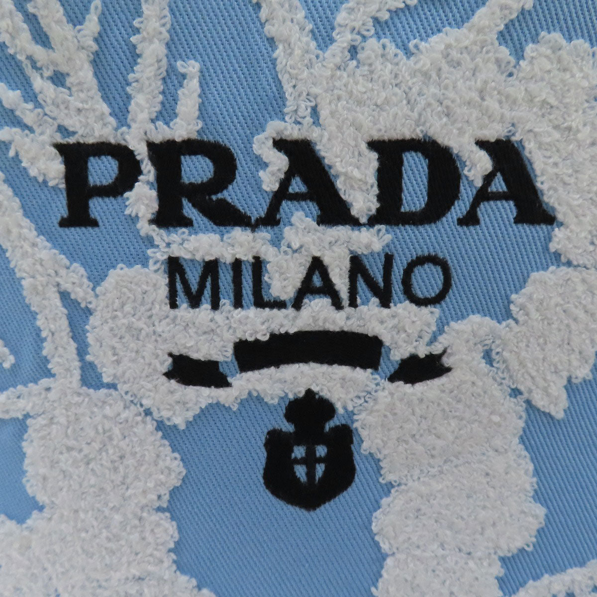 Close-up of Prada Milano logo on a textured fabric background