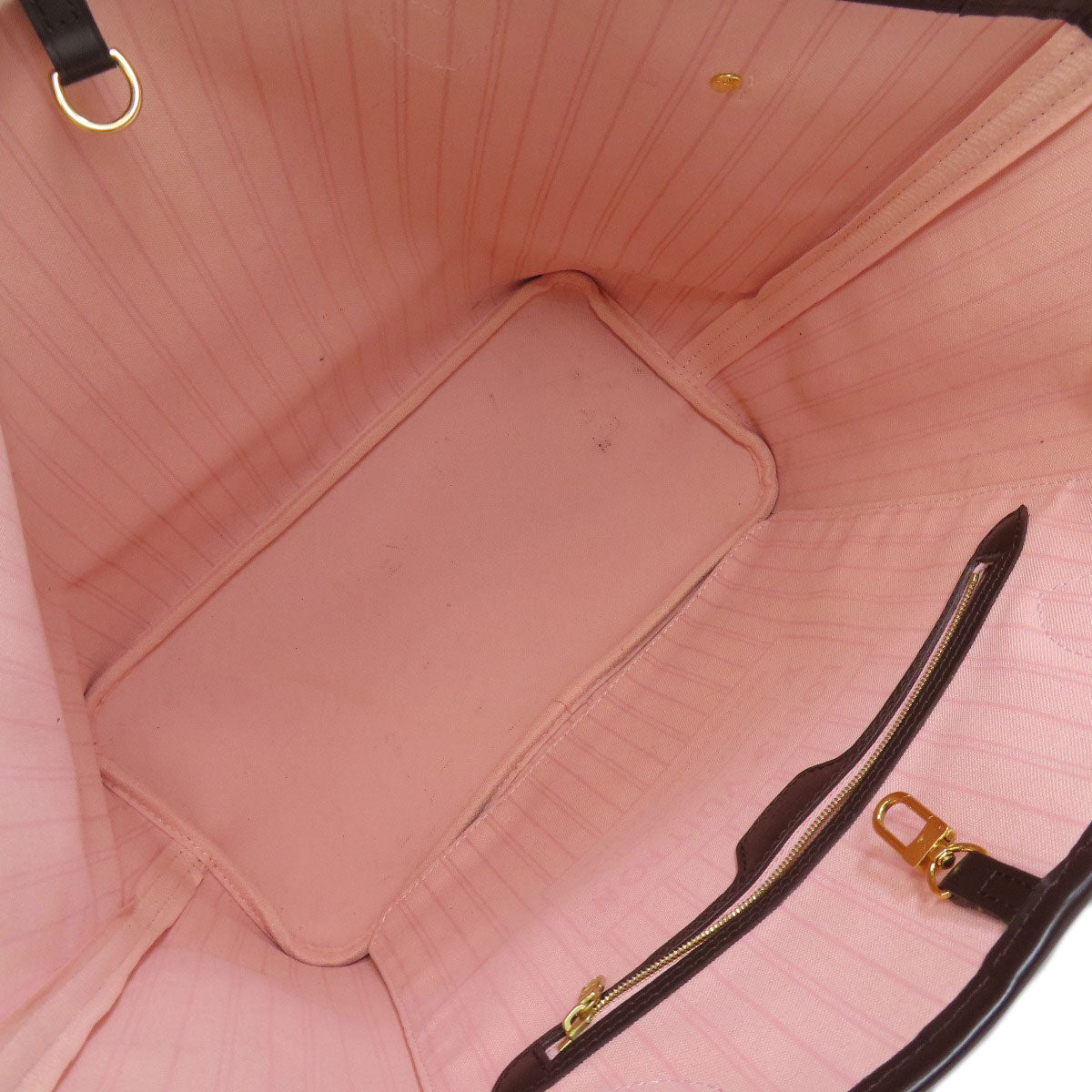 Close-up of a pink handbag interior with gold zipper and hardware.