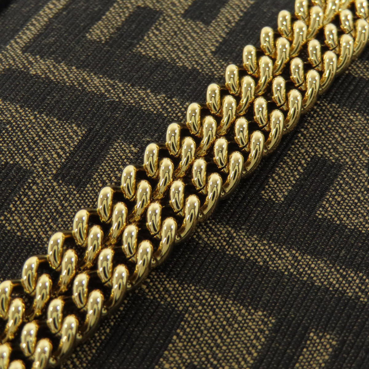 Close-up of a gold chain on a black and gold patterned fabric background