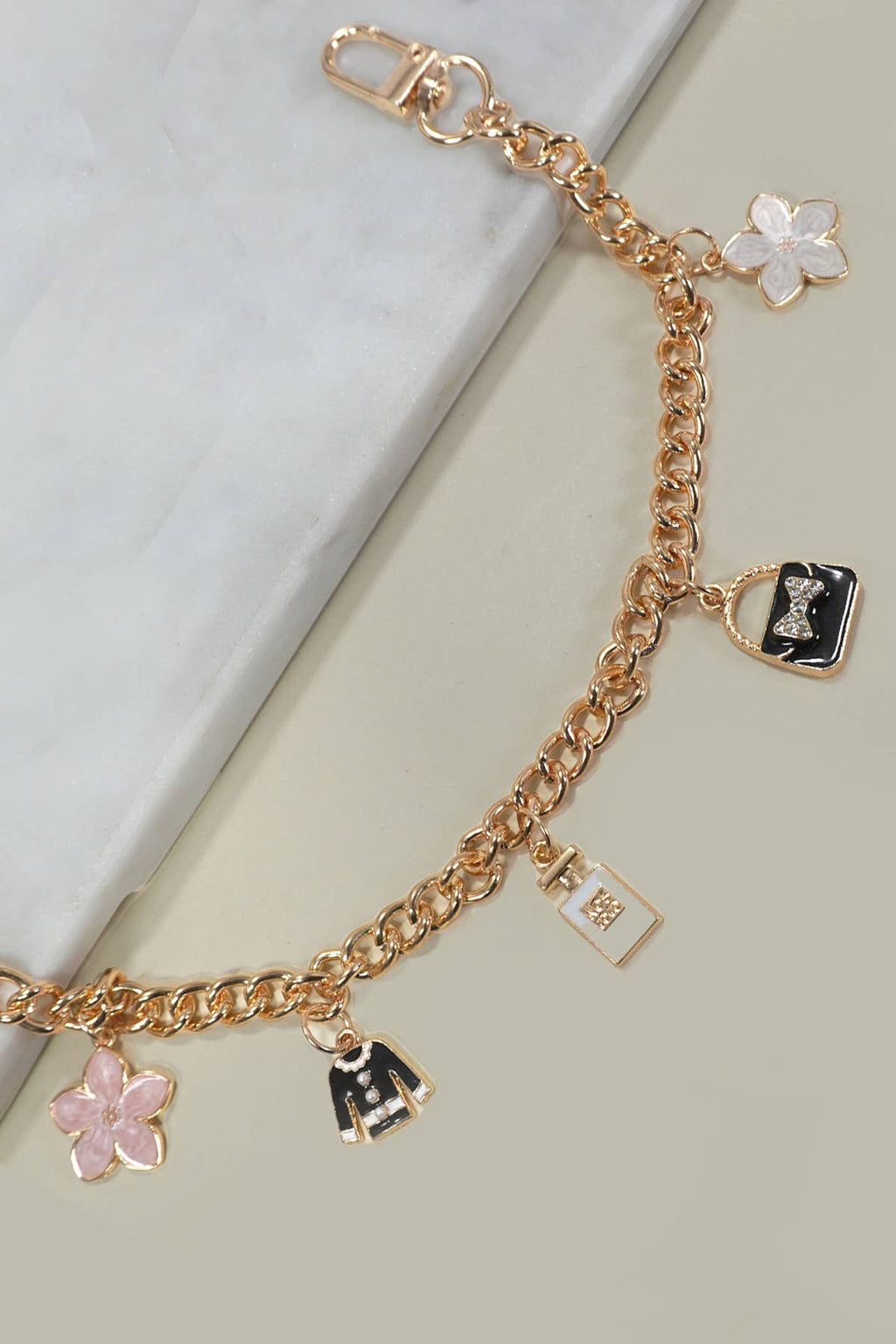 Gold bracelet with various charms on a light background
