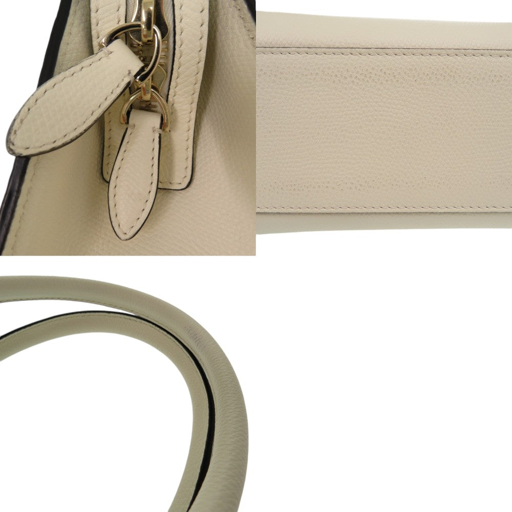 Beige handbag with gold handle and strap on a white background