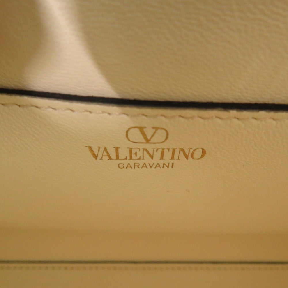 Close-up of Valentino Garavani logo on beige leather surface