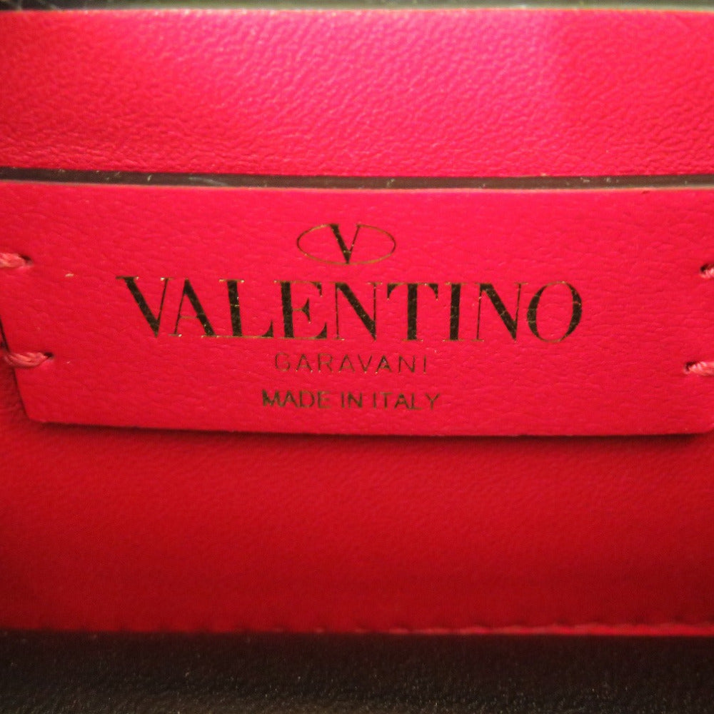 Red leather handbag with 'Valentino' branding on a dark background