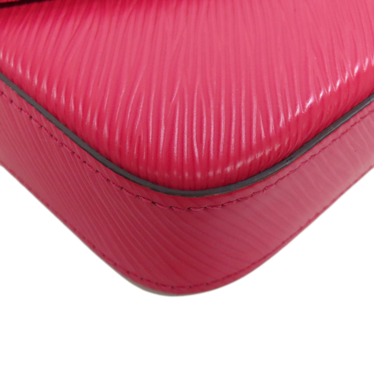 Close-up of a pink textured suitcase corner on a white background