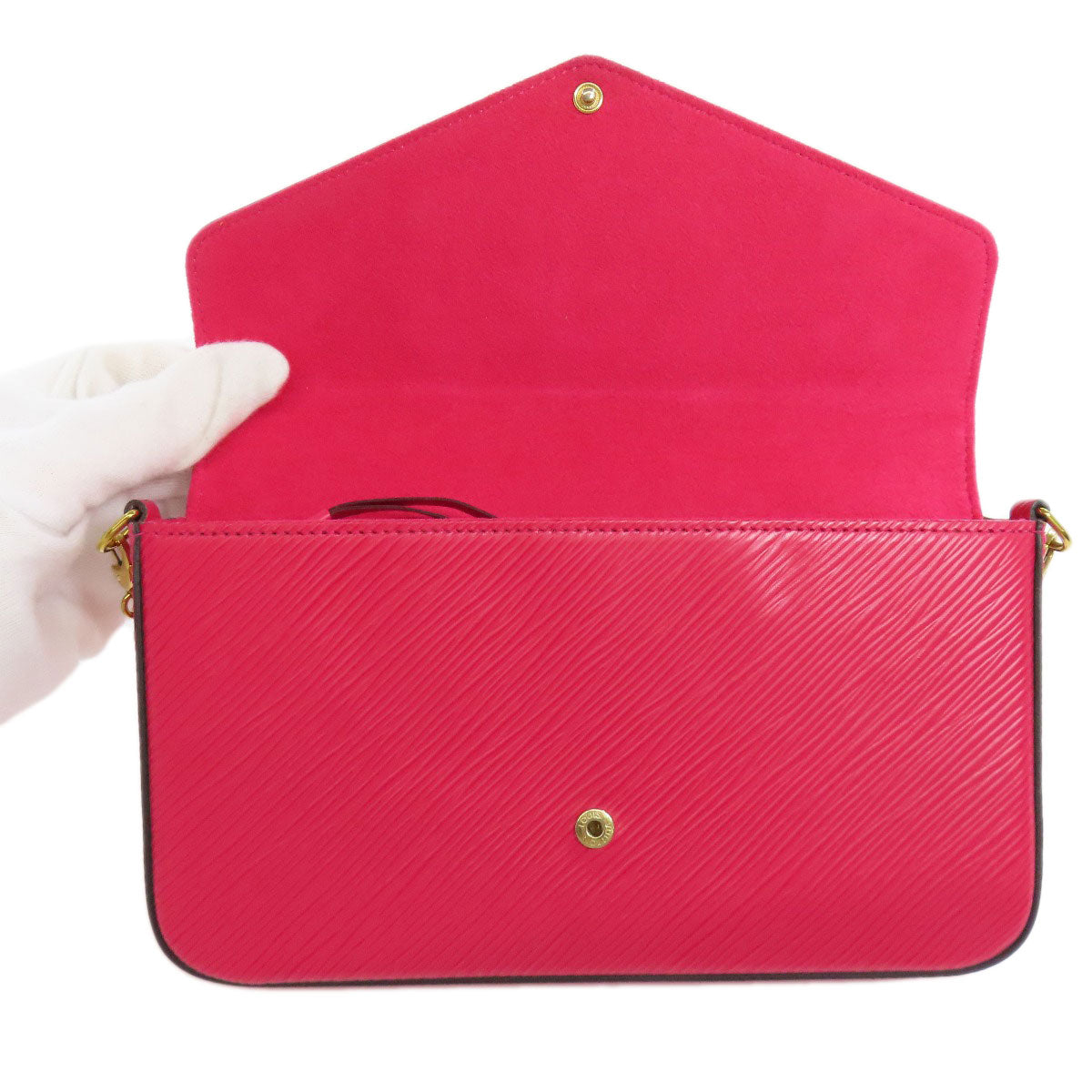 Red handbag with gold accents held by a gloved hand on a white background