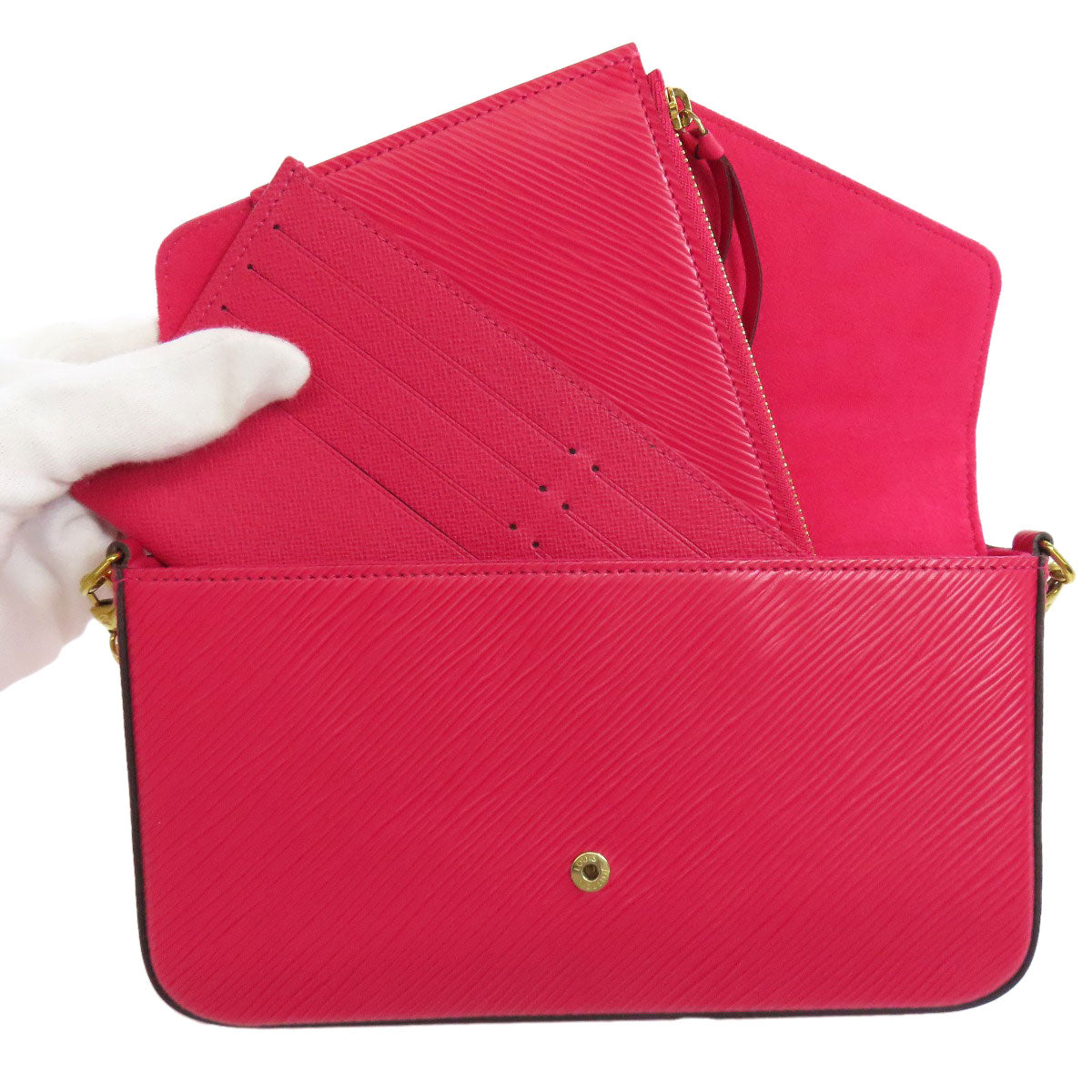 Red handbag with gold accents held by a white-gloved hand on a white background