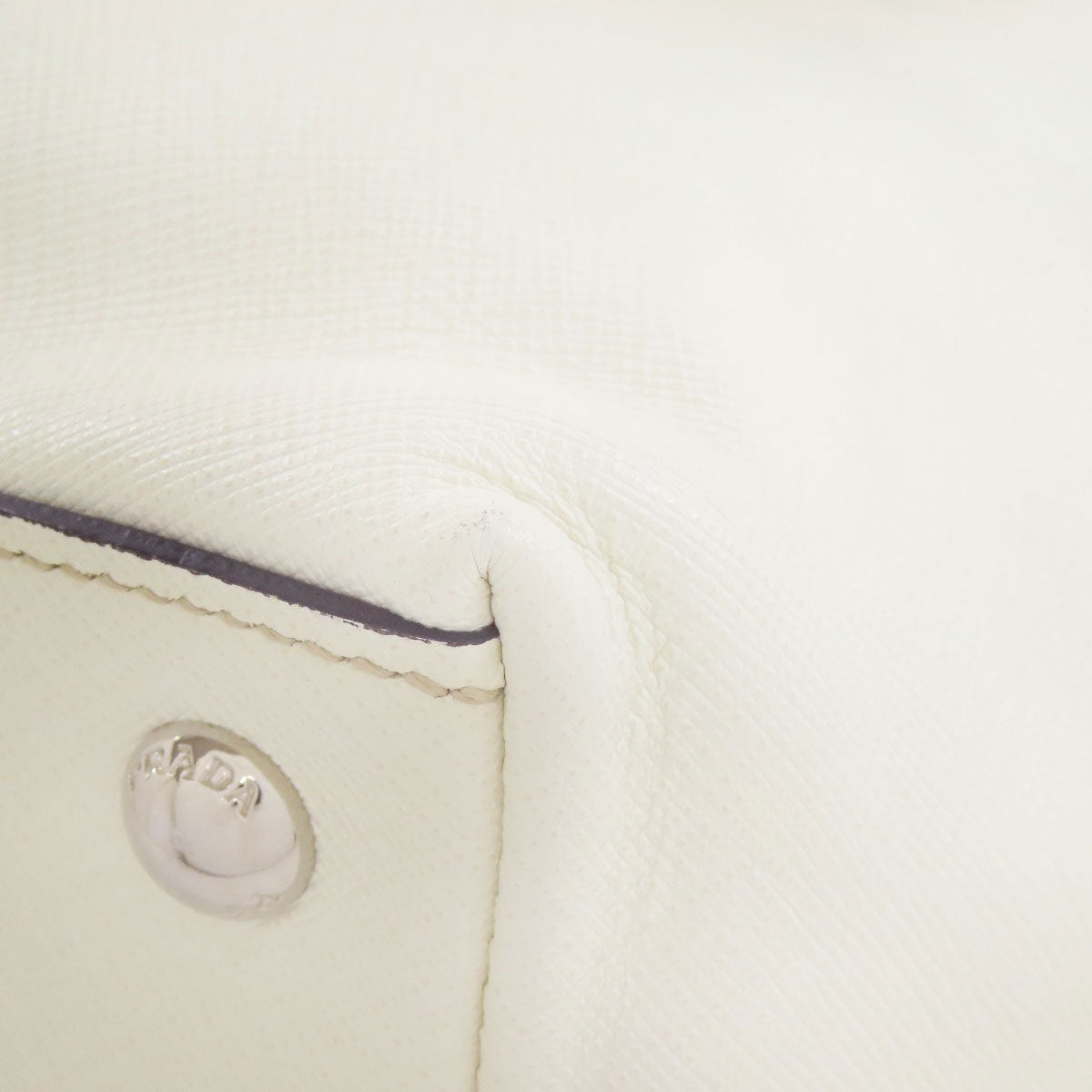 Close-up of a beige leather product with a silver logo on a white background