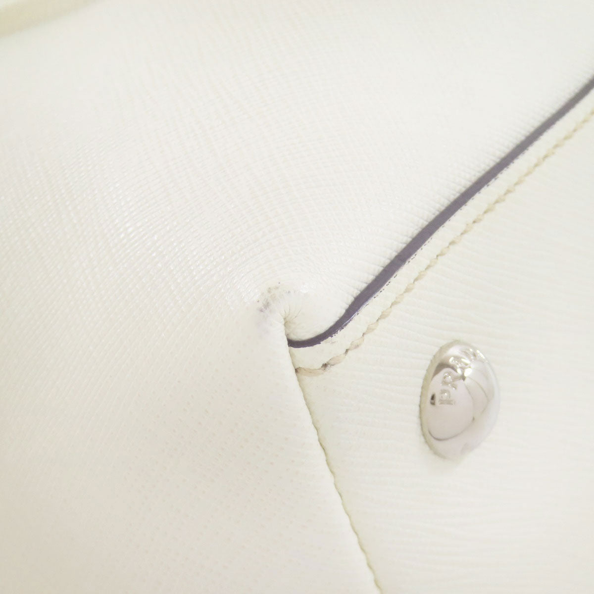 Close-up of a white garment with a button and trim detail.