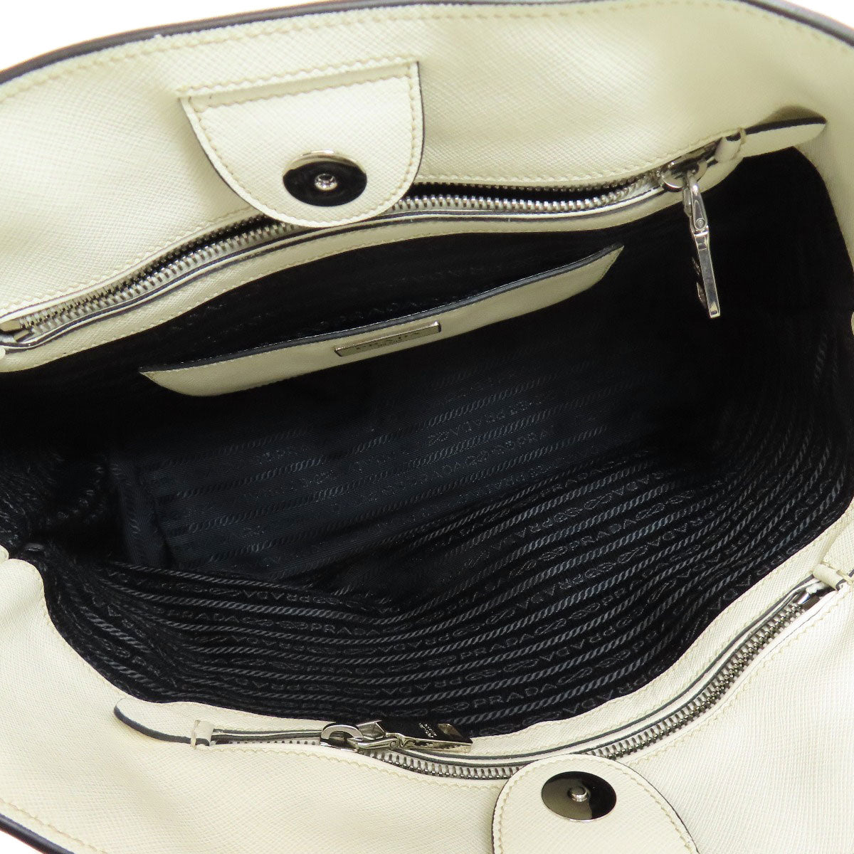 Close-up of a white handbag with a zipper, showing the interior.