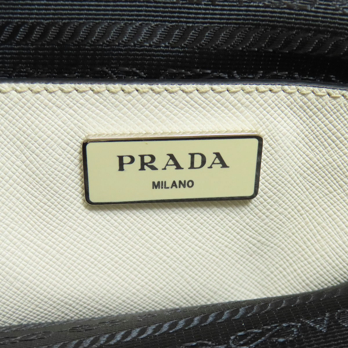 Close-up of a Prada bag with the brand name on a textured surface.