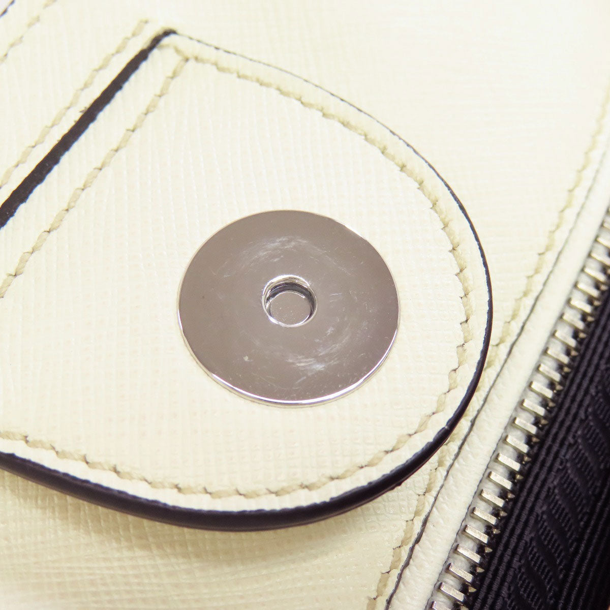 Close-up of a button on a beige fabric surface with a zipper.