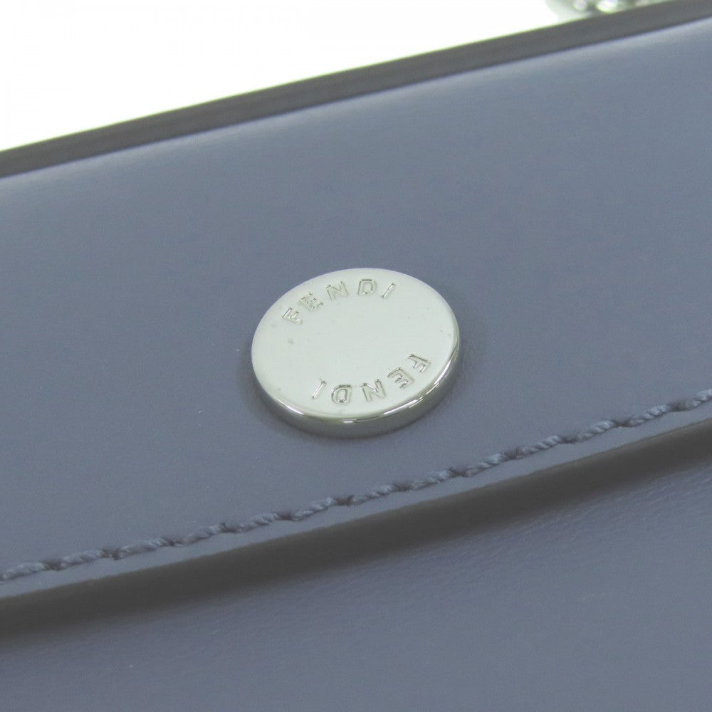 Close-up of a blue leather product with a silver button featuring text.
