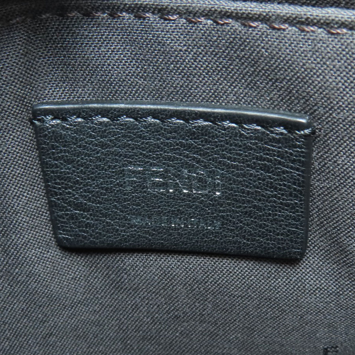 Close-up of a dark gray fabric with a leather label featuring 'Coach' branding.