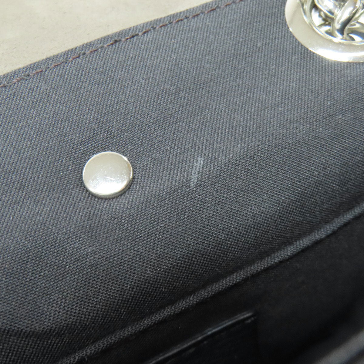 Close-up of a dark gray fabric surface with a metal button and blurred background