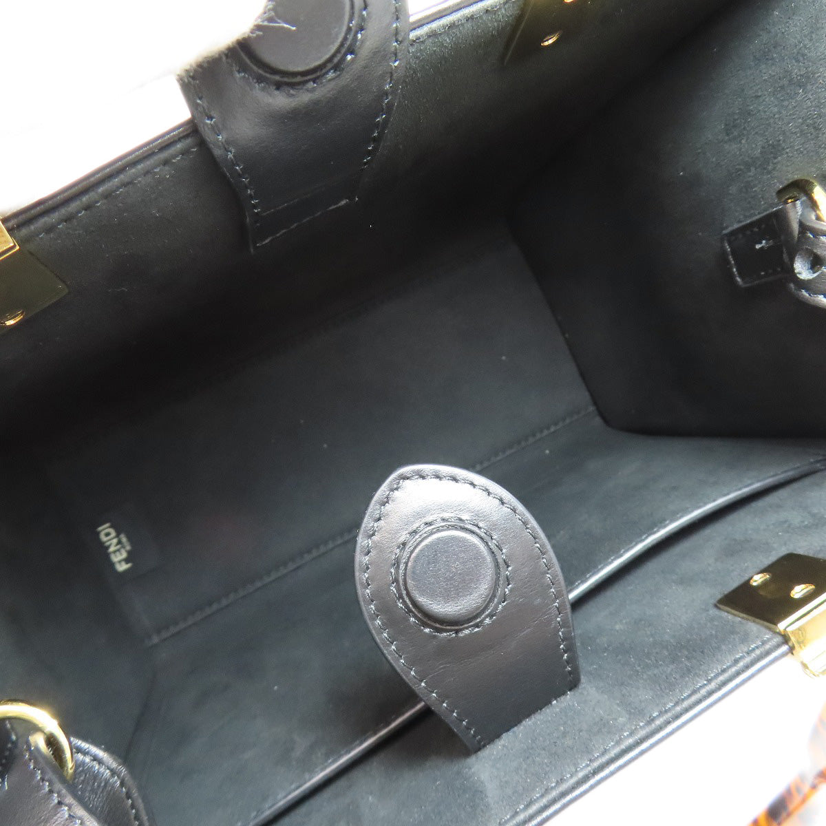 Close-up of a black leather handbag with gold hardware, featuring the Fendi logo.
