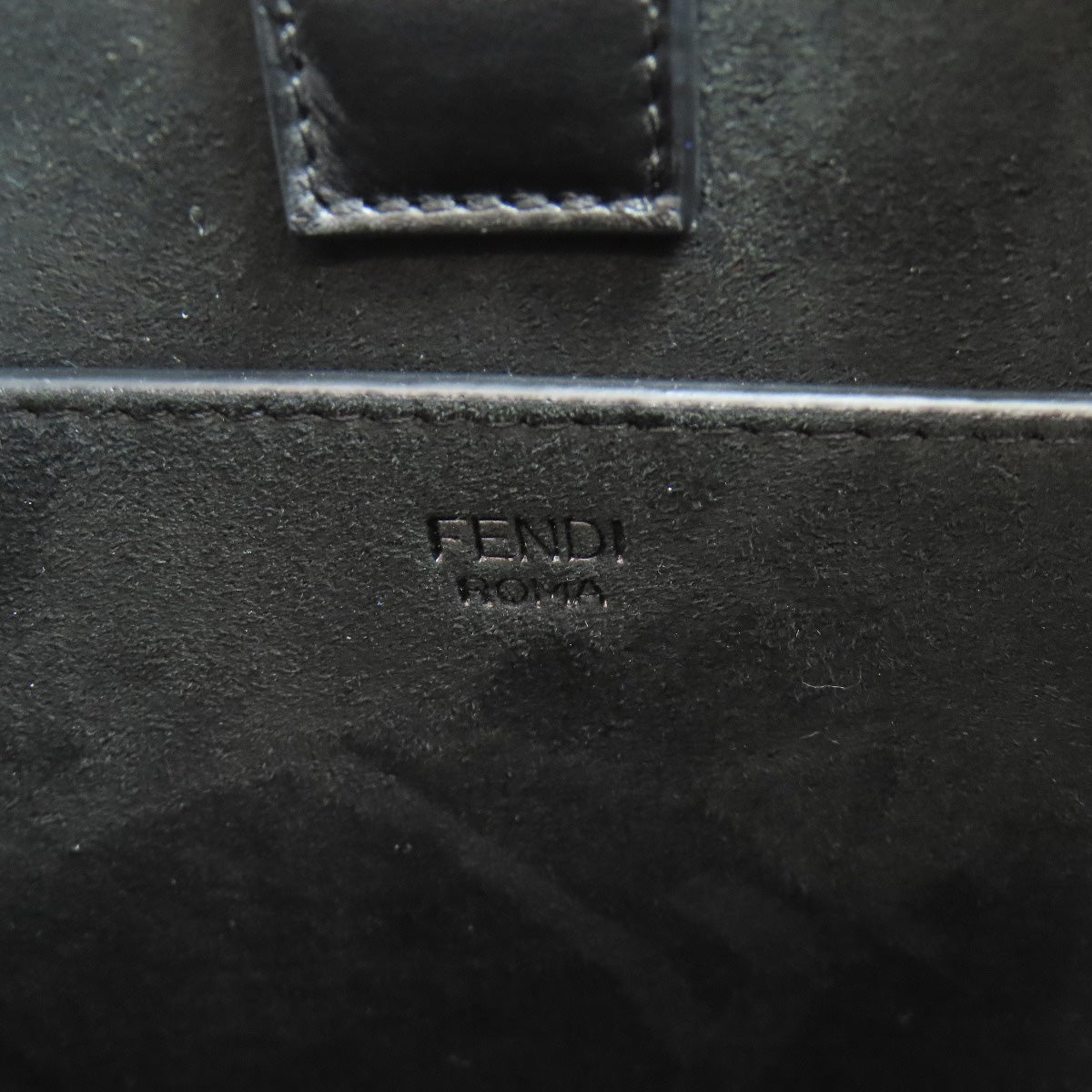 Close-up of a black leather surface with 'Fendi' branding.