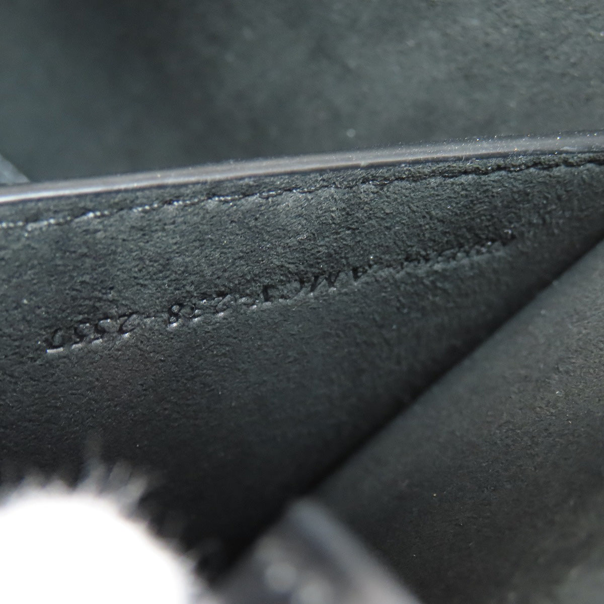 Close-up of a black leather surface with embossed text.